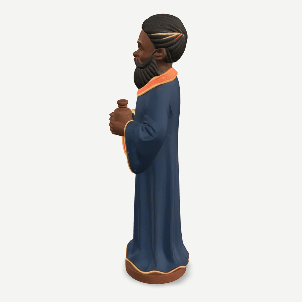 3D printed nativity figurine of Balthazar standing with a jar of myrrh, navy robe and crown — side view